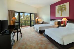 Habitación de hotel con 2 camas, escritorio y TV. en Manado Tateli Resort and Convention en Manado