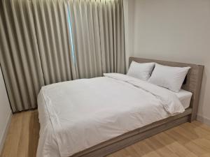 een bed met witte lakens en kussens naast een raam bij Gwang Jang Hotel in Busan