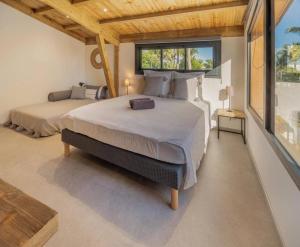 a bedroom with a large bed and a large window at Villa Nauraa - 5ch - piscine - proche plage. in Trois Bassins