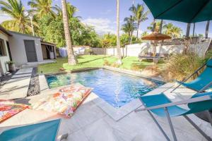 a swimming pool with two chairs and an umbrella at Villa Nauraa - 5ch - piscine - proche plage. in Trois Bassins