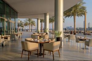 a restaurant with tables and chairs and palm trees at Marriott Marquis Dubai Creek in Dubai