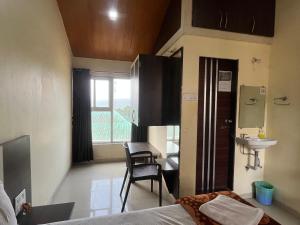 a room with a bed and a desk and a sink at Gugal Residency Mahabaleshwar in Mahabaleshwar