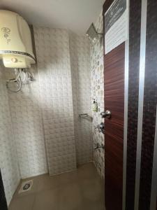 baño con ducha y puerta marrón en Gugal Residency Mahabaleshwar, en Mahabaleshwar