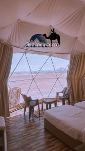 un dormitorio con una tienda de campaña con un caballo en The Rock Camp, en Wadi Rum