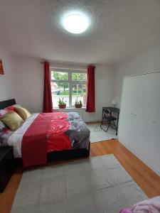 1 dormitorio con 1 cama y una ventana con cortinas rojas en JosteeStay Apartments -Rooms en Goodmayes