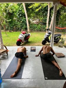 Dos hombres tumbados en una colchoneta de yoga con motocicletas. en Villa Freedom, en Ahangama