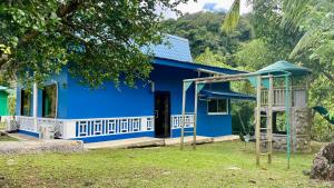 ein blaues Haus mit einem Spielplatz davor in der Unterkunft Ngermid Oasis - Vibrant 2 BD/1 BA Duplex in Ngermid