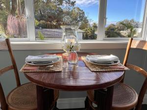 a wooden table with chairs and a vase on it at The Boat House Studio in Tairua