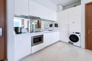 uma cozinha com armários brancos e uma máquina de lavar e secar roupa em Soho Suites KLCC by Leala em Kuala Lumpur