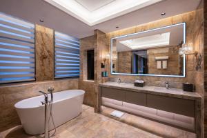 a bathroom with a tub and a large mirror at Novotel Kunshan Yangcheng Lake in Kunshan