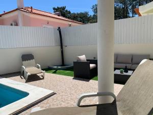 une cour avec une piscine, des chaises et une clôture dans l'établissement Villa Luxsomar, à Charneca