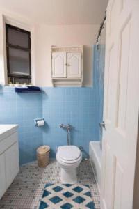 a bathroom with a toilet and a blue tile wall at Comfortable 1-Bedroom Apt in Manhattan in New York