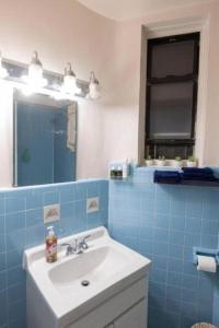 a blue tiled bathroom with a sink and a mirror at Comfortable 1-Bedroom Apt in Manhattan in New York