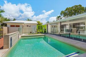 a swimming pool in front of a house at Trinity Beach Stunner - Tropical Entertainer in Trinity Beach