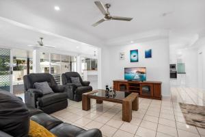 uma sala de estar com um sofá e uma televisão em Trinity Beach Stunner - Tropical Entertainer em Trinity Beach