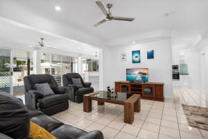 a living room with a couch and a tv at Trinity Beach Stunner - Tropical Entertainer in Trinity Beach