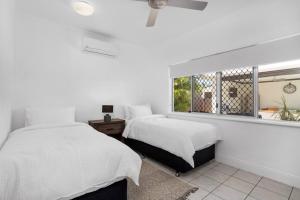 two beds in a white room with a window at Trinity Beach Stunner - Tropical Entertainer in Trinity Beach +25 photos
