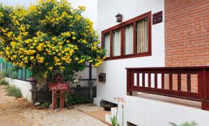 Baan Bhuwann Holiday Apartment في تشالوكلوم: شجرة بالورود الصفراء بجانب مبنى