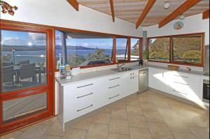 a kitchen with white cabinets and a view of the ocean at Coota Views in Mallacoota