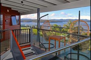 a balcony of a house with a swing and a table at Coota Views in Mallacoota