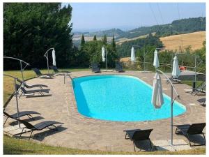 a large swimming pool with chairs and umbrellas at Villa Fienile Design in SantʼAppiano