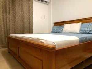 a wooden bed in a room with at Modern Cozy 2Bedroom Space near KNUST & Kumasi Airport in Kumasi