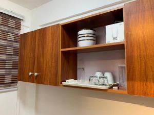 a kitchen with wooden cabinets with plates and glasses at Modern Cozy 2Bedroom Space near KNUST & Kumasi Airport in Kumasi