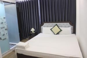 1 dormitorio con 1 cama grande con sábanas y almohadas blancas en Hanoi Little Hotel, en Hanói