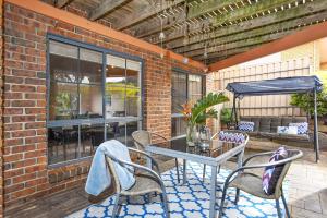 un patio con mesa y sillas en una pared de ladrillo en Encounter Bay Family Retreat ' Pets Welcome', en Encounter Bay