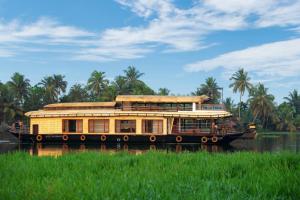 a large yellow boat on a river with palm trees at Boats N Beds in Alleppey