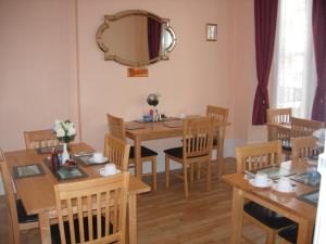 a dining room with wooden tables and chairs and a mirror at Longfield Guest House in Dover