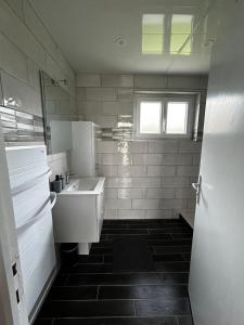 a white bathroom with a sink and a refrigerator at Le cottage des quatre vents in Gouchaupré