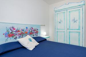 a bedroom with a blue bed with a painting on the wall at New Villa Carmen in San Teodoro