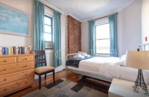um quarto com uma cama, uma cadeira e janelas em Amazing 3 BR Apartment in Prime Location em Nova York