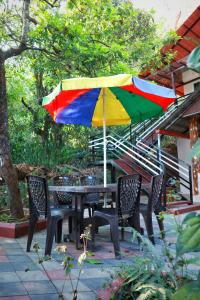 a table and chairs with a colorful umbrella at Katakeri Deluxe Holiday Homes in Madikeri