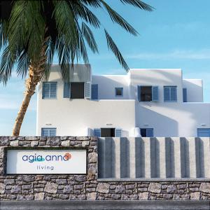 un edificio bianco con una palma e un cartello di Agia Anna Living ad Agia Anna Naxos