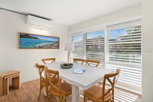 a dining room with a table and chairs and a large window at Perfect Coastal Getaway-Metres to Shoal Bay Beach in Nelson Bay +11 photos