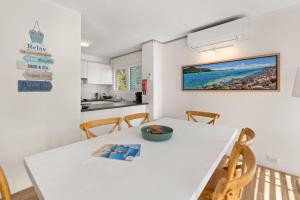 a kitchen and dining room with a white table and chairs at Perfect Coastal Getaway-Metres to Shoal Bay Beach in Nelson Bay
