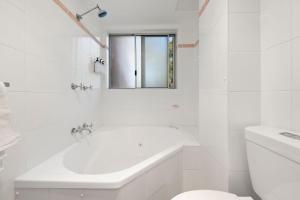 a white bathroom with a tub and a sink at Perfect Coastal Getaway-Metres to Shoal Bay Beach in Nelson Bay