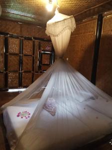 a bed with a mosquito net in a room at Mahkota Atia Bungallow in Praya