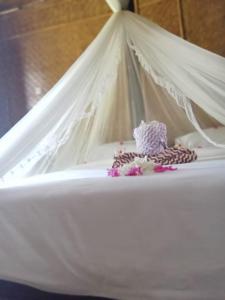 a white bed with a white canopy and some pink flowers at Mahkota Atia Bungallow in Praya