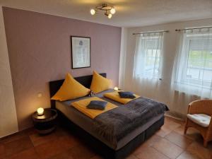 sypialnia z łóżkiem z żółtymi poduszkami w obiekcie Weingut u. Gästehaus Becker w mieście Platten