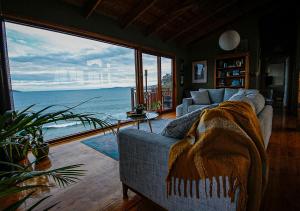 a living room with a couch and a view of the ocean at Waterfront - Bluff Beach House, Park Beach in Dodges Ferry