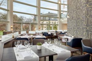 um restaurante com mesas e cadeiras e janelas grandes em Sheraton Offenbach Hotel em Offenbach