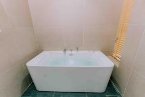 a white bath tub in a bathroom with a window at Pacific Apartment & Hotel Phu Quoc in Phu Quoc
