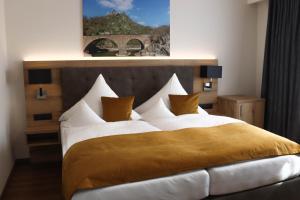 ein Schlafzimmer mit einem großen Bett mit weißer Bettwäsche und gelben Kissen in der Unterkunft Hotel-Restaurant Zur Traube in Altenahr