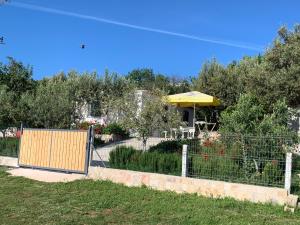 a fence in front of a garden with a yellow umbrella at Villas Ermali in Ksamil