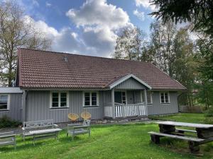 una pequeña casa blanca con mesa de picnic y sillas en Villa Lägervik Vitsand en Gunsjögården
