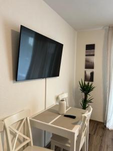 E&K Apartment I في دوسلدورف: طاولة طعام بيضاء مع تلفزيون على الحائط