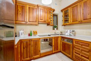 una cocina con armarios de madera y fregadero en Ta'Sandrija Pool And Well-Being In Gozo - Happy Rentals en Taʼ Bullara